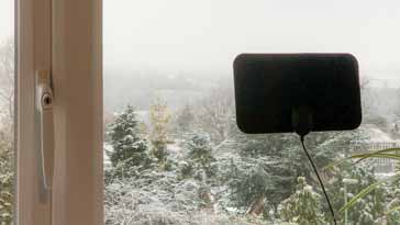 A flat indoor TV antenna mounted on a window